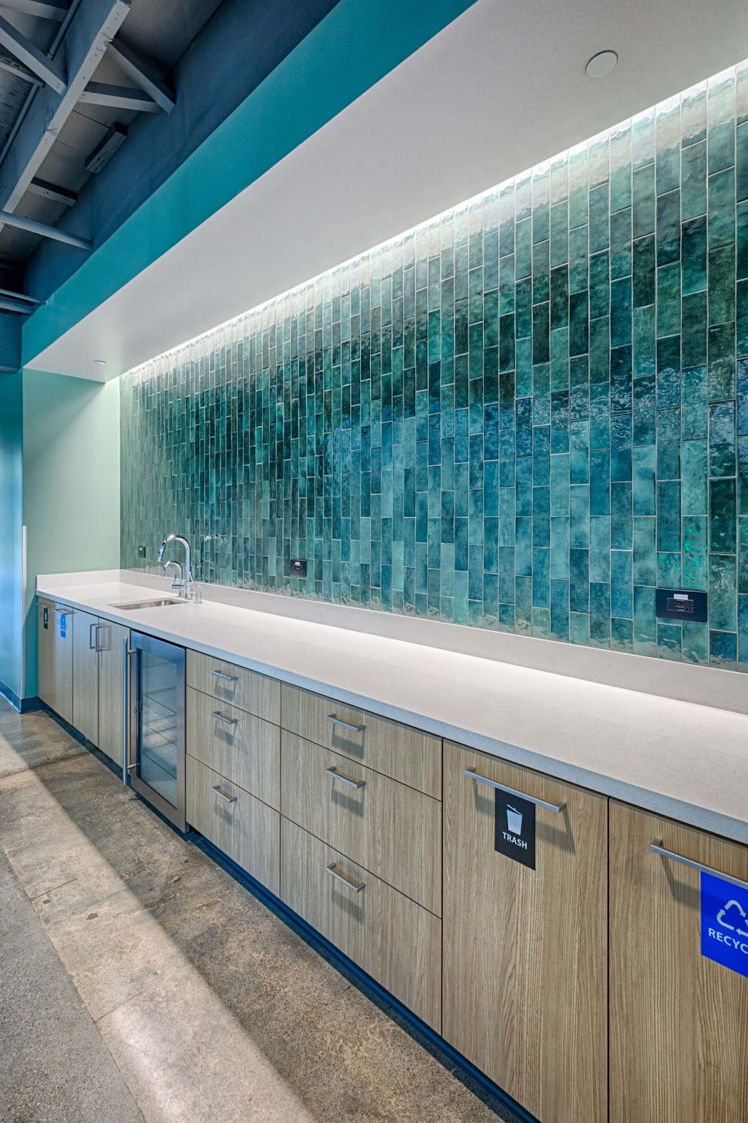 A modern kitchen featuring blue wall tiles, showcasing the quality of commercial construction and design expertise.