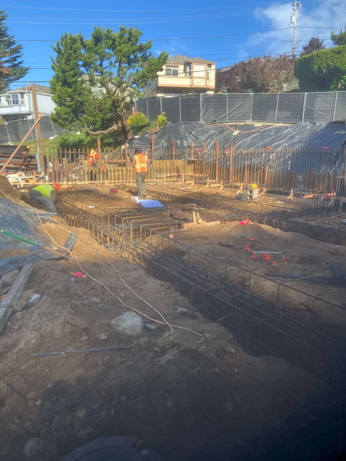 A bustling construction site featuring concrete foundations and steel beams, indicative of commercial real estate development.