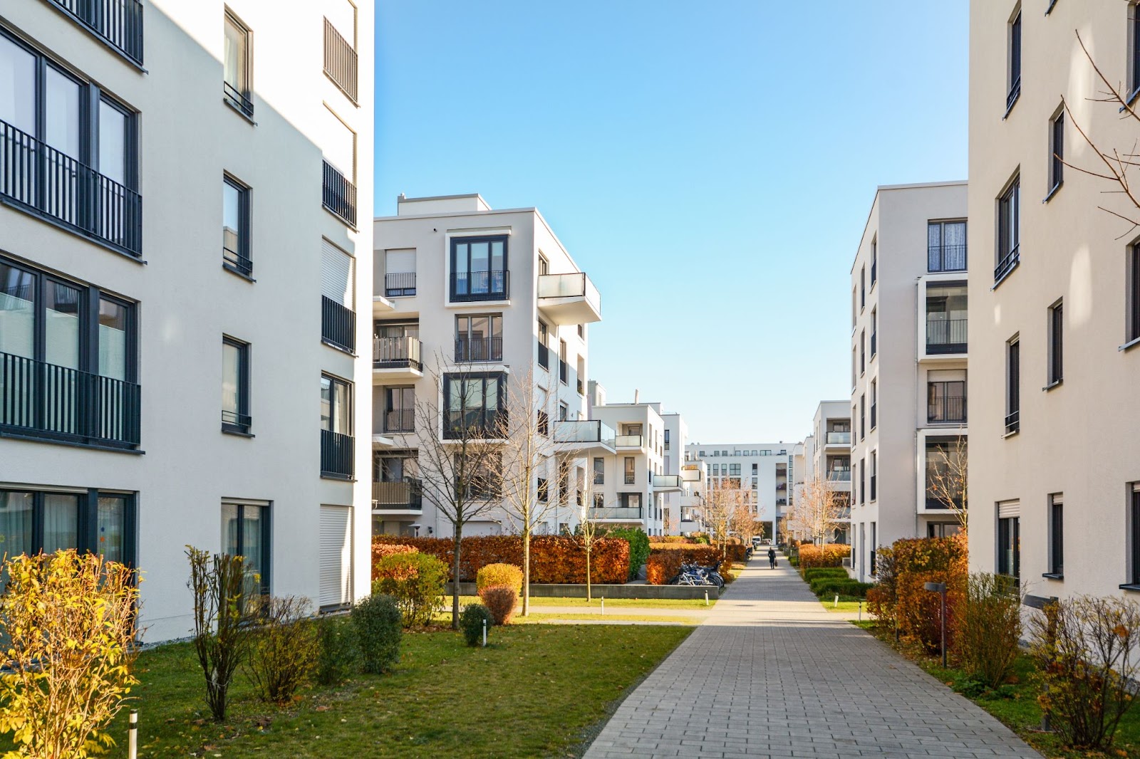 A walkway leading to a series of modern apartment buildings, showcasing commercial construction and design elements.