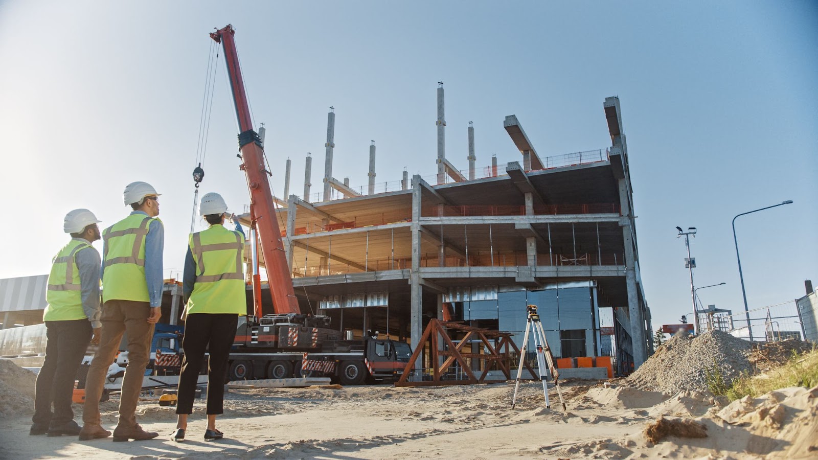 Three construction workers in hard hats stand before a commercial building, representing teamwork in commercial construction.