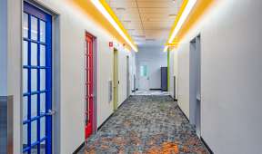 Hallway with blue door and yellow lights on ceiling