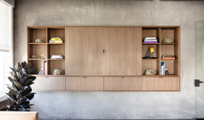 A contemporary office living room featuring a stylish wooden wall unit, blending functionality with modern design elements.