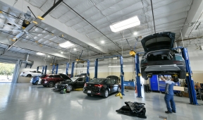 A car repair shop with several vehicles on the floor, office in background.