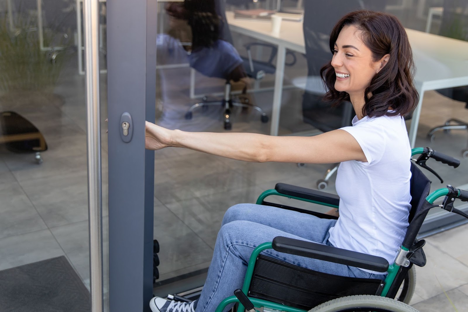 A woman in a wheelchair opens a door, showcasing ADA-compliant upgrades in a commercial building.