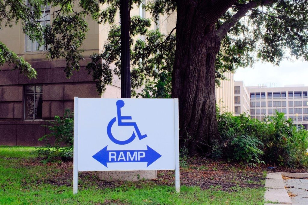 A sign with Ramp and a wheelchair symbol indicating accessible entrance