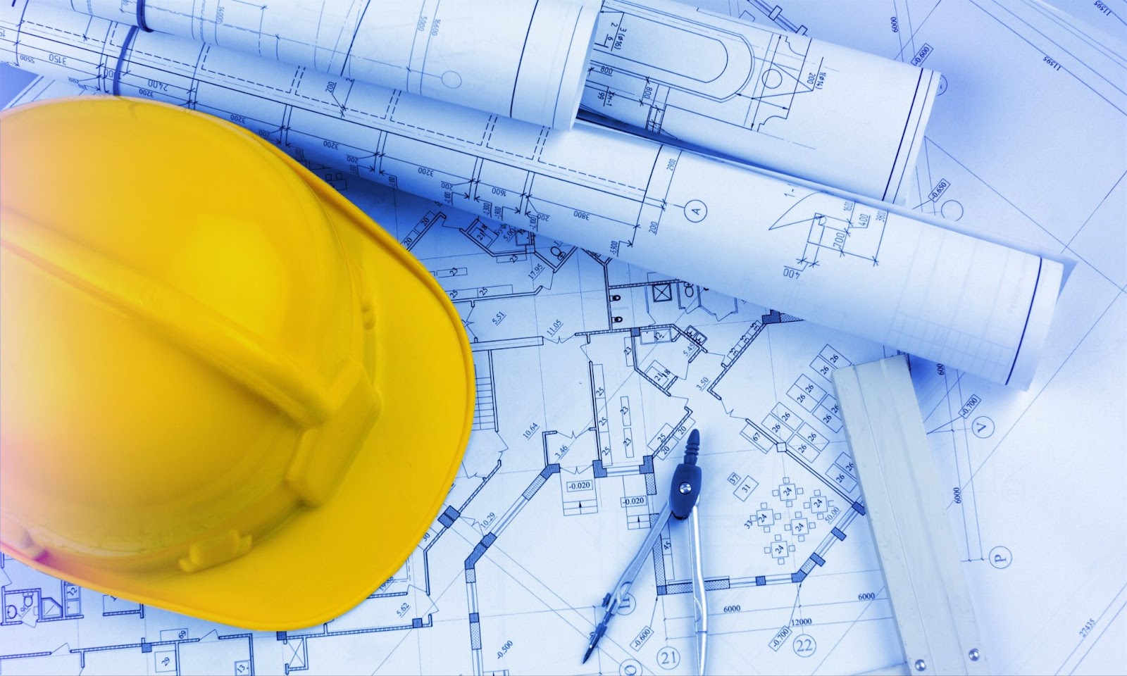 A hard hat and blueprints resting on a blue background, symbolizing expertise in commercial construction projects.