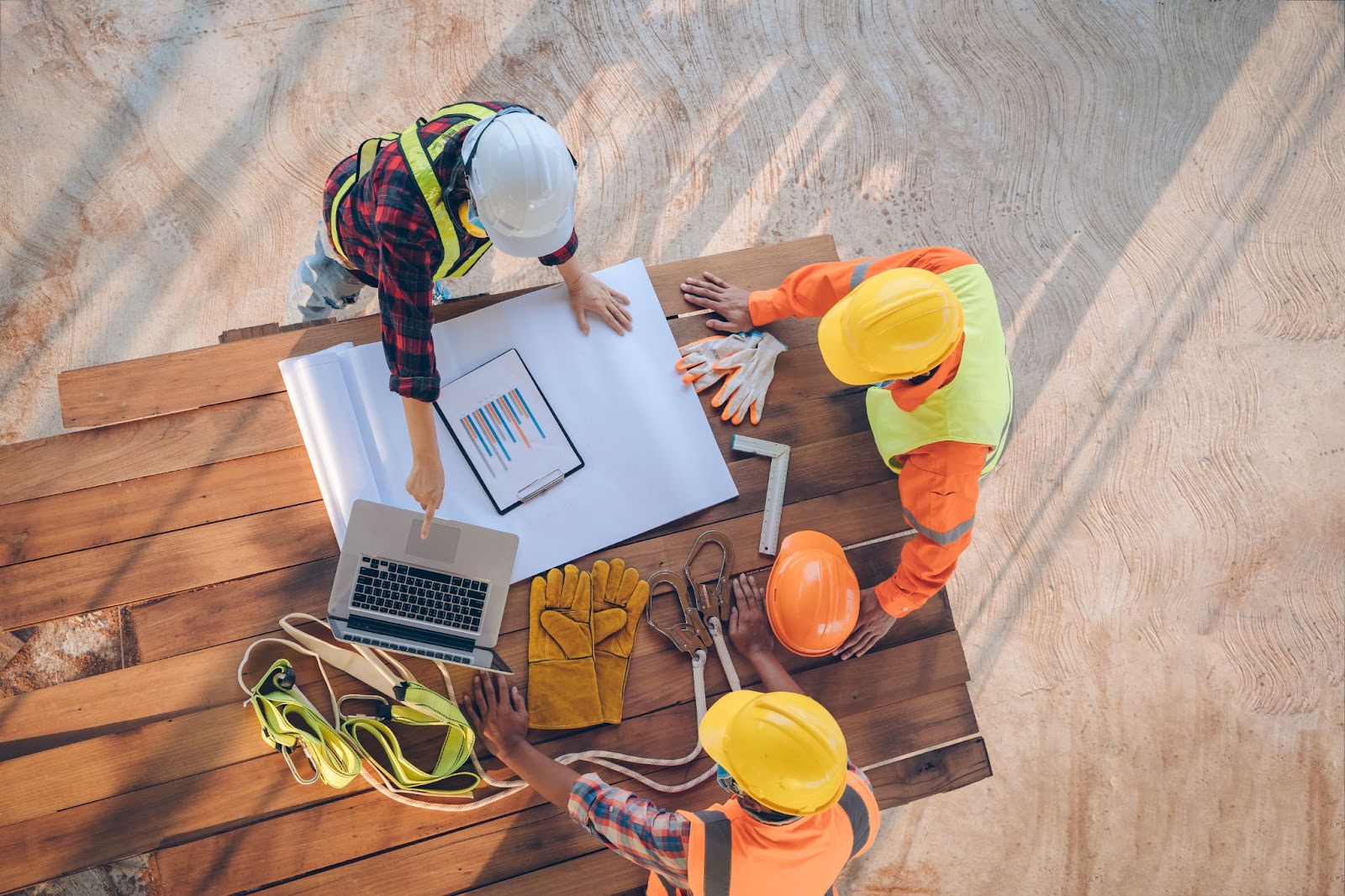 Three construction workers confidently standing on a wooden table, showcasing their expertise in commercial construction.