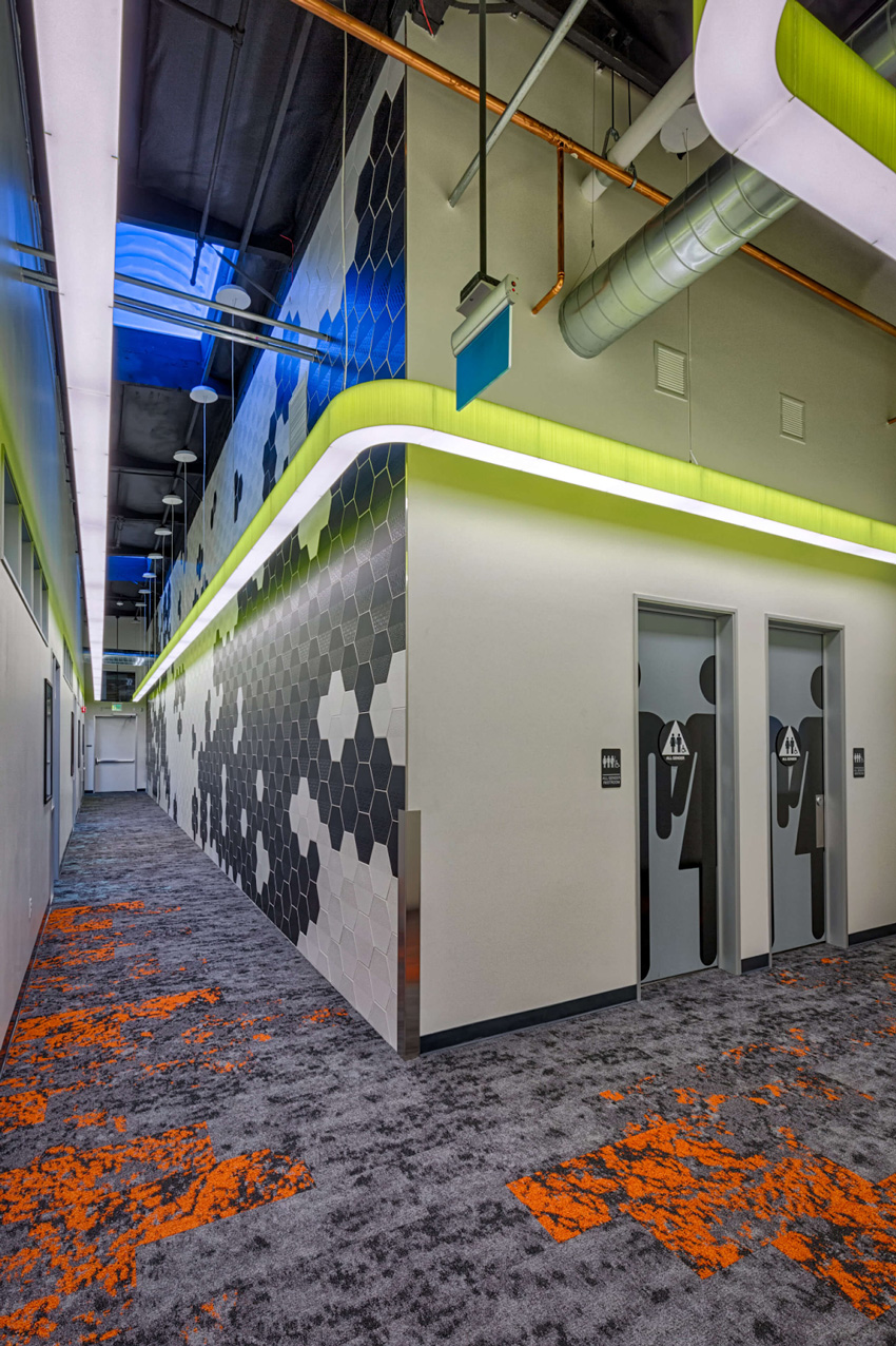 A lively hallway with orange and green carpeting and a bright white ceiling