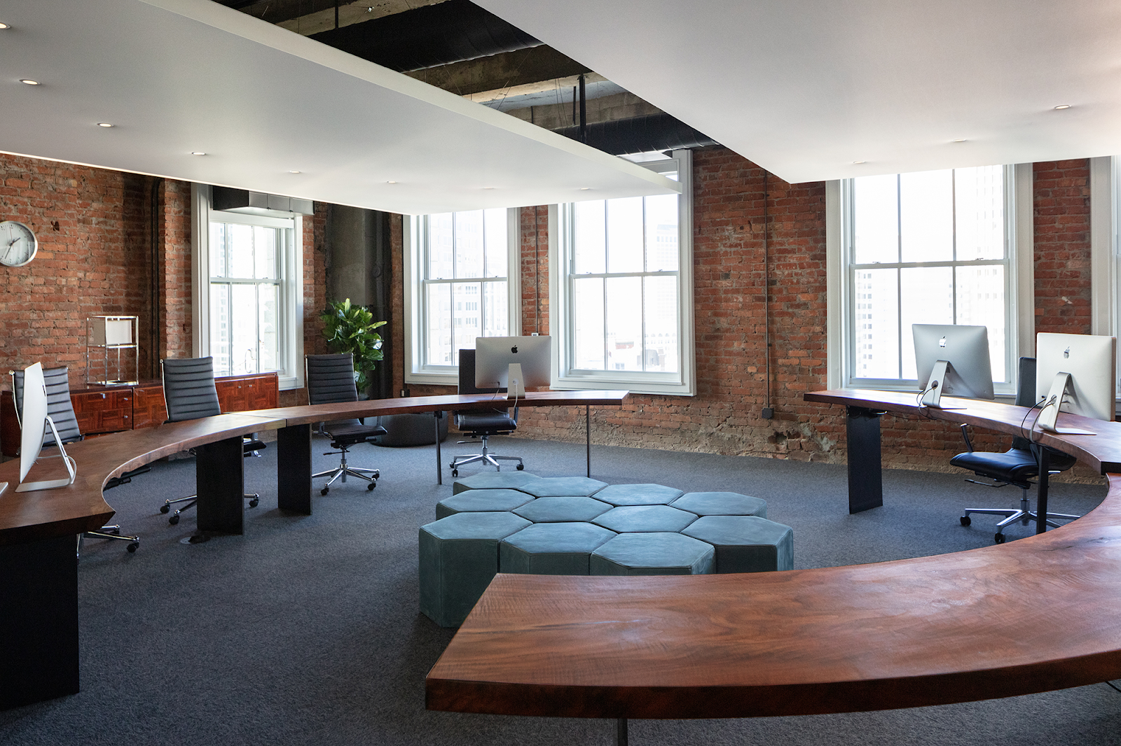 An office featuring a modern curved table surrounded by several ergonomic chairs